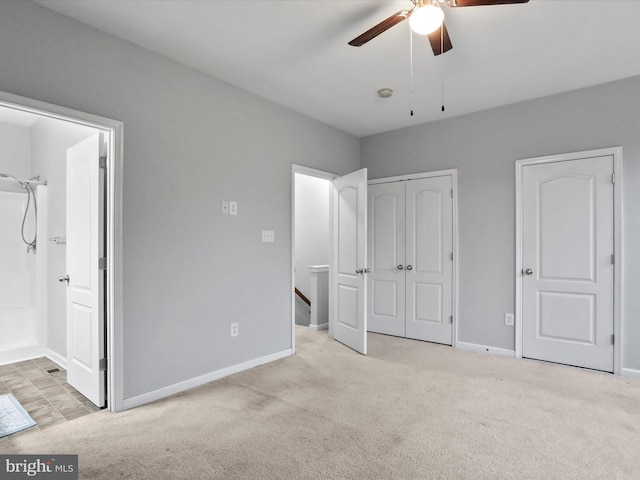 unfurnished bedroom with ceiling fan, ensuite bathroom, and light colored carpet