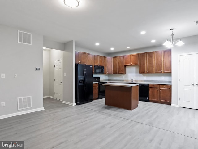 kitchen featuring black appliances, decorative light fixtures, light hardwood / wood-style flooring, a notable chandelier, and a center island