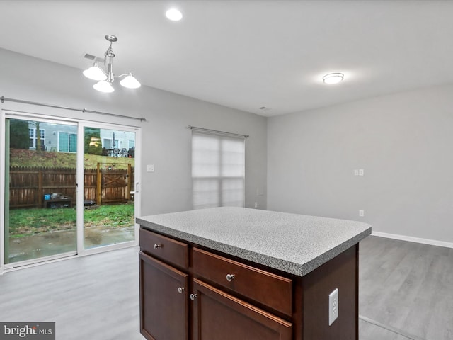 kitchen featuring a kitchen island, light wood-type flooring, hanging light fixtures, and a chandelier