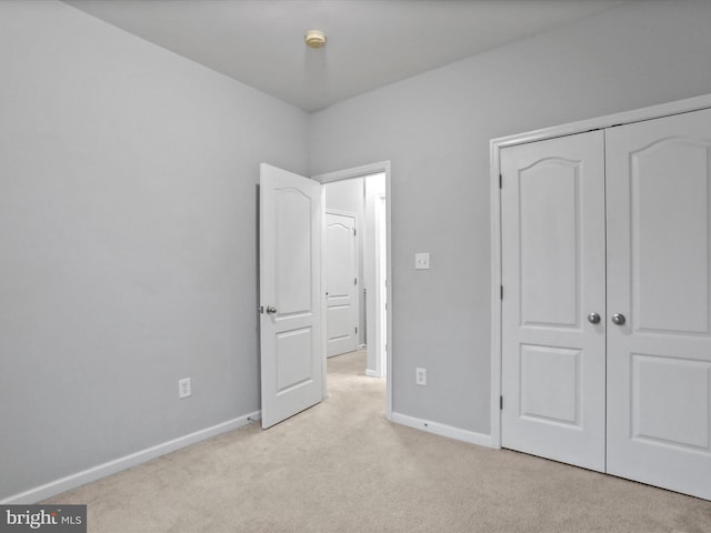 unfurnished bedroom featuring light carpet and a closet