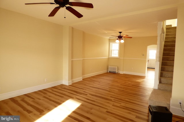 unfurnished room featuring ceiling fan, radiator heating unit, and light hardwood / wood-style flooring