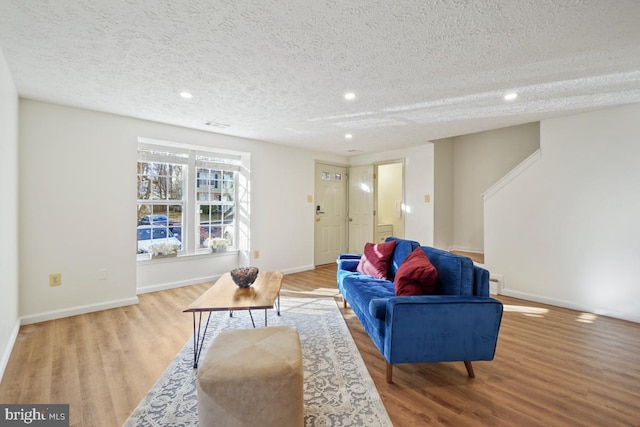 living room featuring light wood-type flooring and a textured ceiling