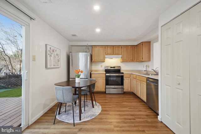 kitchen with sink, stainless steel appliances, a textured ceiling, and light wood-type flooring