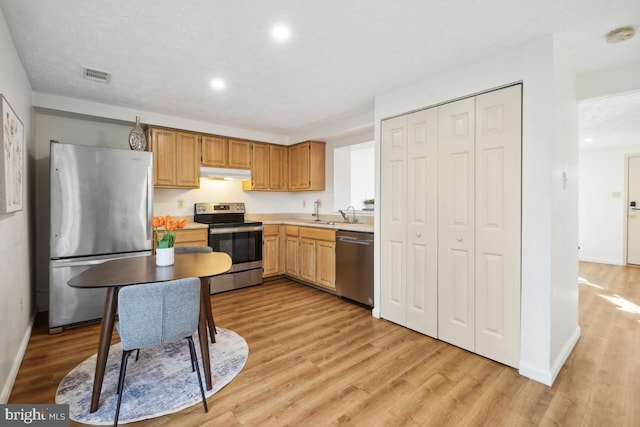 kitchen featuring a textured ceiling, stainless steel appliances, and light hardwood / wood-style flooring