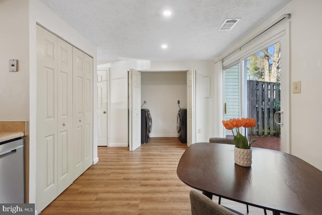 dining space featuring light wood-type flooring, separate washer and dryer, and a textured ceiling