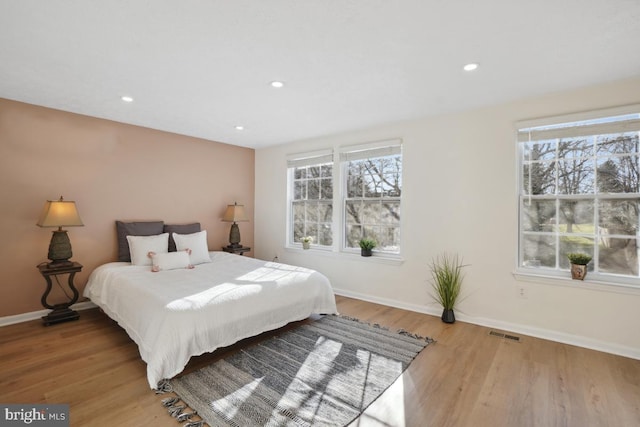 bedroom with multiple windows and light hardwood / wood-style floors