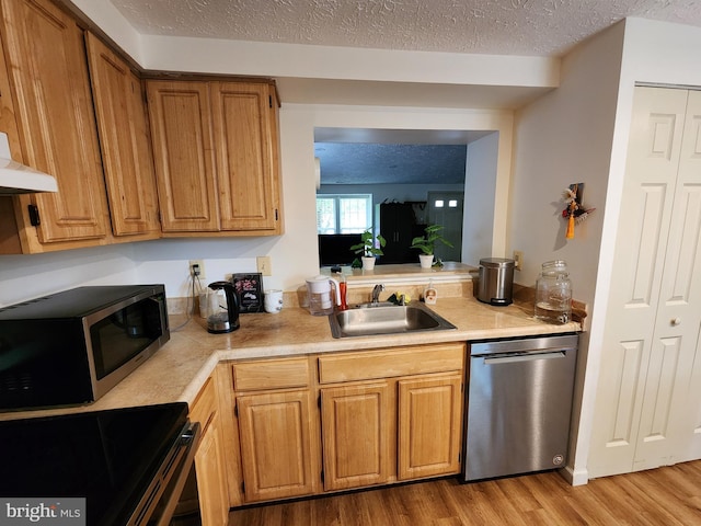 kitchen featuring a textured ceiling, sink, light wood-type flooring, and stainless steel appliances