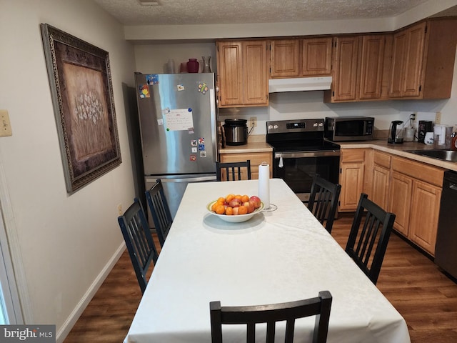 kitchen with appliances with stainless steel finishes, dark hardwood / wood-style flooring, and a textured ceiling