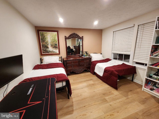 bedroom with a textured ceiling and light hardwood / wood-style flooring