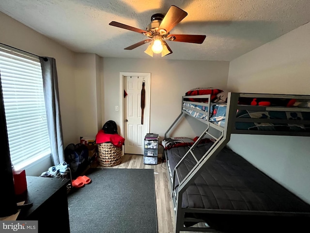 bedroom featuring ceiling fan, a textured ceiling, and wood finished floors