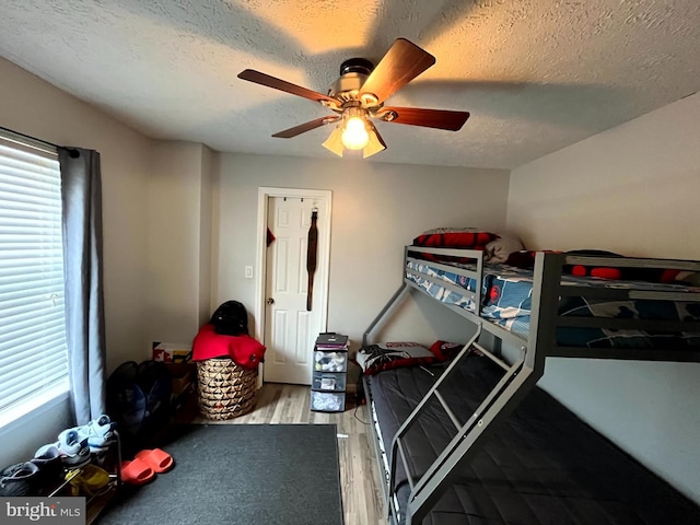 bedroom featuring ceiling fan, wood-type flooring, and a textured ceiling