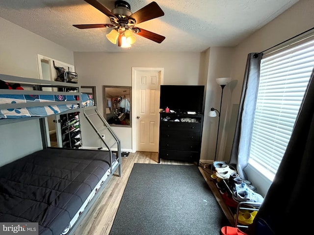 bedroom with multiple windows, a textured ceiling, light hardwood / wood-style flooring, and ceiling fan