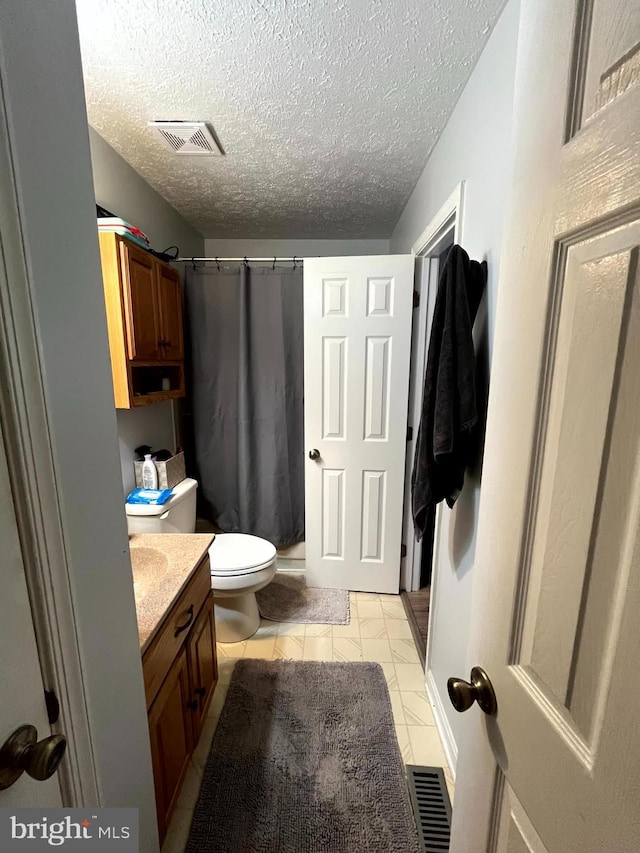 full bathroom featuring curtained shower, toilet, vanity, and visible vents