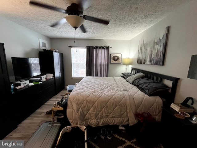 bedroom featuring a textured ceiling, wood finished floors, and a ceiling fan