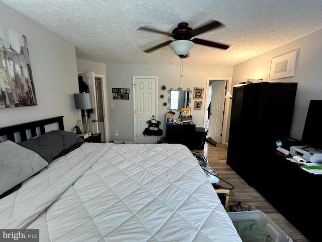 bedroom featuring a ceiling fan, wood finished floors, and a textured ceiling