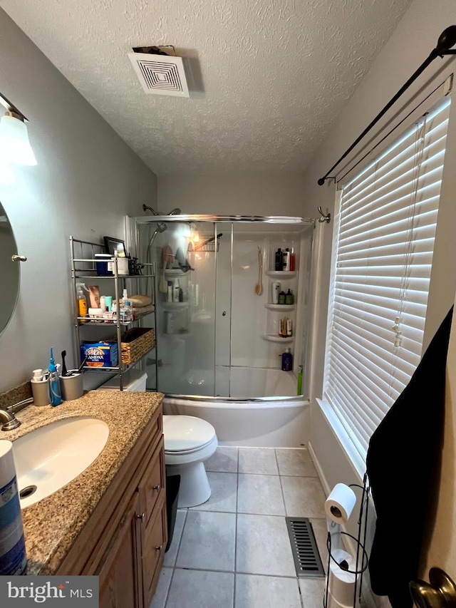 full bathroom featuring vanity, tile patterned flooring, toilet, enclosed tub / shower combo, and a textured ceiling