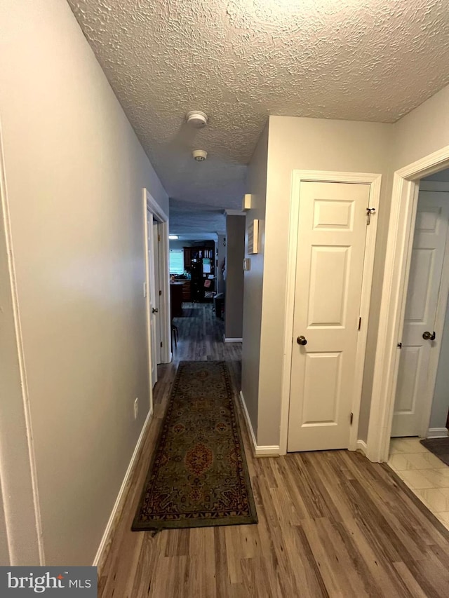 hall with hardwood / wood-style floors and a textured ceiling