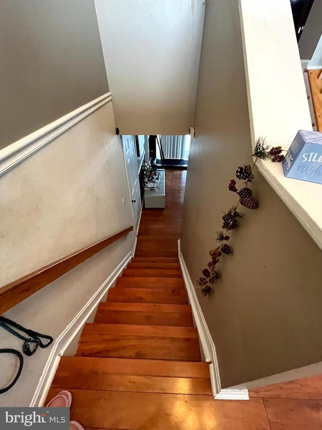 staircase with baseboards and wood finished floors