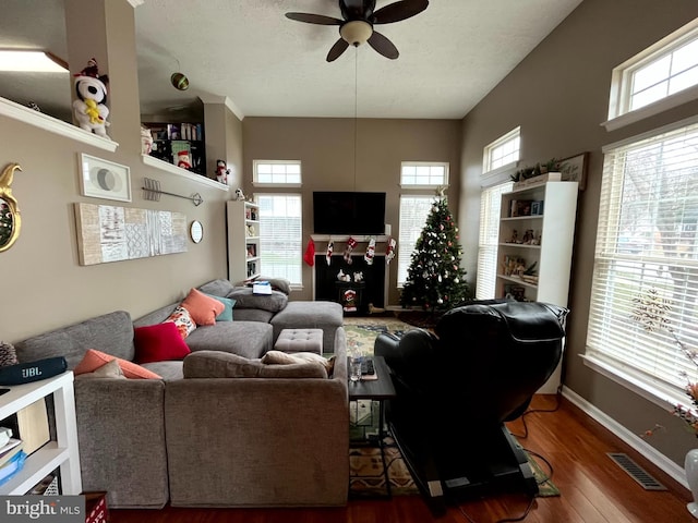 living room featuring visible vents, ceiling fan, baseboards, wood finished floors, and a textured ceiling