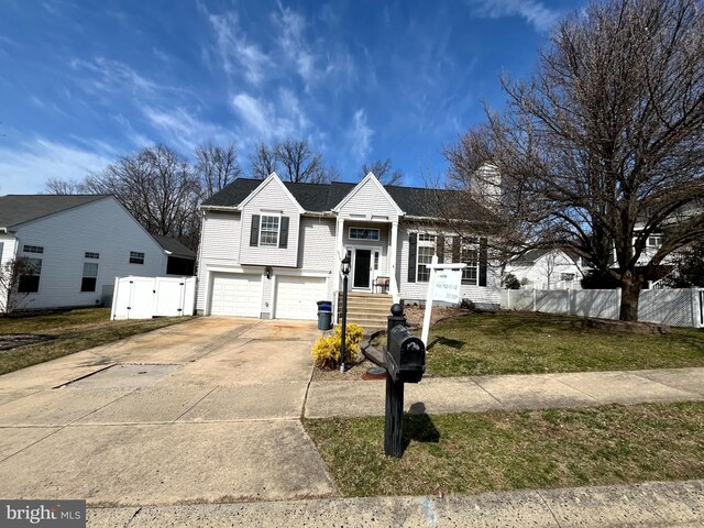 view of front of home featuring concrete driveway, an attached garage, fence, and a front lawn