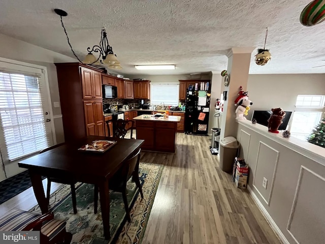 dining space with a chandelier, hardwood / wood-style floors, a healthy amount of sunlight, and a textured ceiling