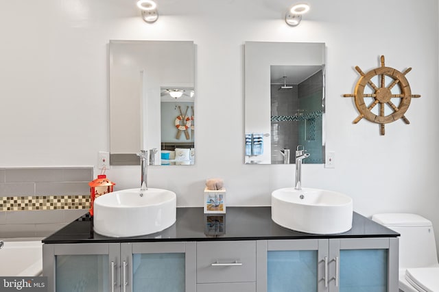 bathroom featuring vanity, toilet, backsplash, and a tub