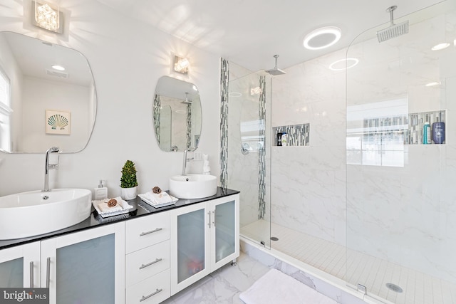 bathroom with a tile shower and vanity