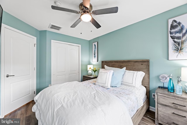 bedroom with ceiling fan, dark wood-type flooring, and a closet