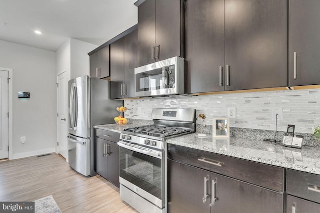 kitchen featuring light stone countertops, light wood-type flooring, tasteful backsplash, dark brown cabinetry, and stainless steel appliances