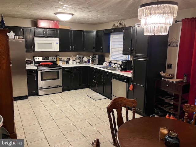 kitchen featuring appliances with stainless steel finishes, a textured ceiling, sink, light tile patterned floors, and a chandelier