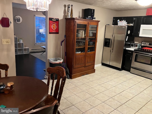 kitchen with a textured ceiling, stainless steel appliances, a baseboard heating unit, a chandelier, and light tile patterned flooring