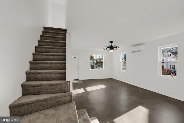 stairs featuring concrete flooring and an AC wall unit