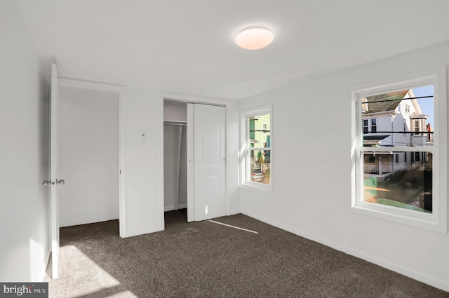 unfurnished bedroom featuring multiple windows and dark colored carpet