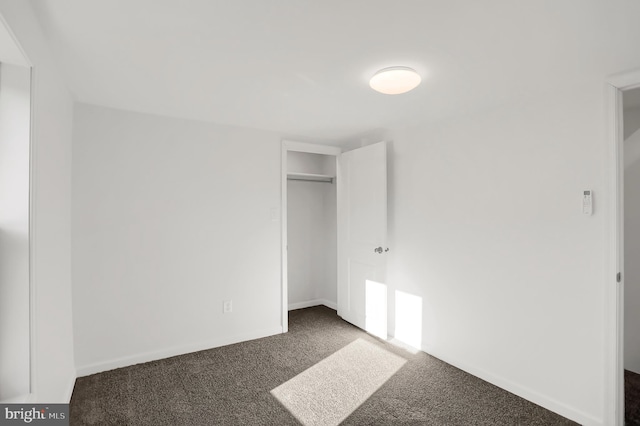 unfurnished bedroom featuring dark colored carpet and a closet