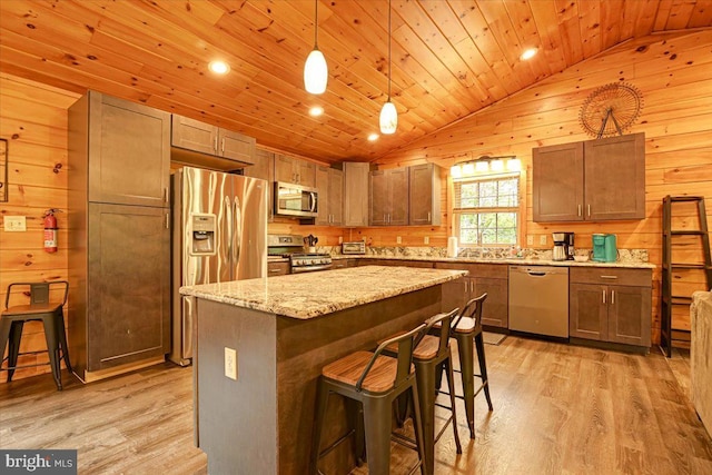 kitchen featuring stainless steel appliances, vaulted ceiling, light hardwood / wood-style flooring, a kitchen island, and hanging light fixtures