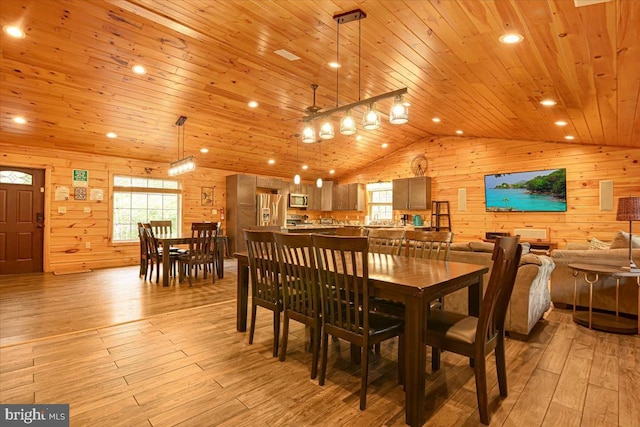 dining room with wooden walls, wood ceiling, and light hardwood / wood-style floors