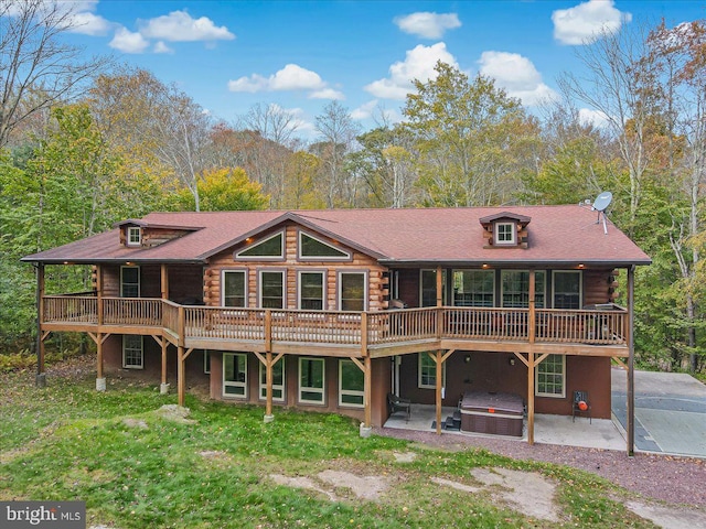 rear view of property with a patio area, a wooden deck, and a hot tub