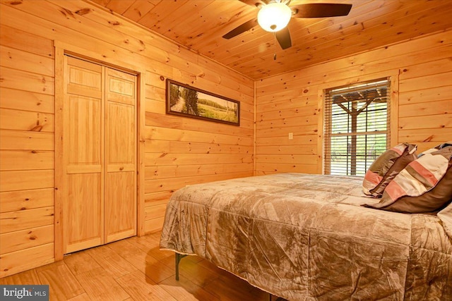 bedroom with ceiling fan, wood walls, wooden ceiling, and light hardwood / wood-style flooring