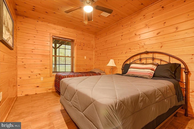 bedroom with light wood-type flooring, ceiling fan, wood walls, and wood ceiling