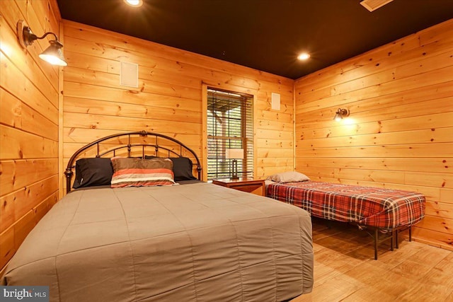 bedroom featuring hardwood / wood-style floors and wooden walls