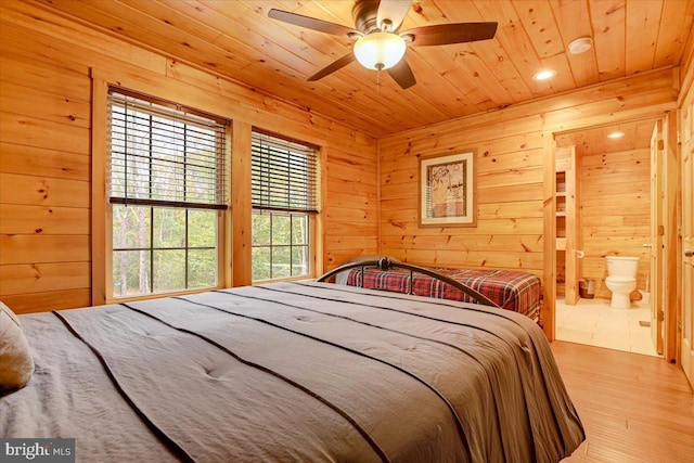 bedroom with multiple windows, wooden walls, and light hardwood / wood-style flooring