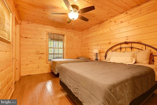 bedroom with ceiling fan, light wood-type flooring, wooden walls, and wooden ceiling