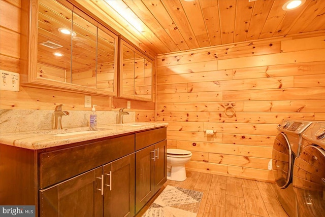 bathroom with hardwood / wood-style floors, separate washer and dryer, and wooden walls