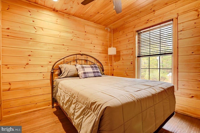 bedroom with wood ceiling, wooden walls, and light hardwood / wood-style floors