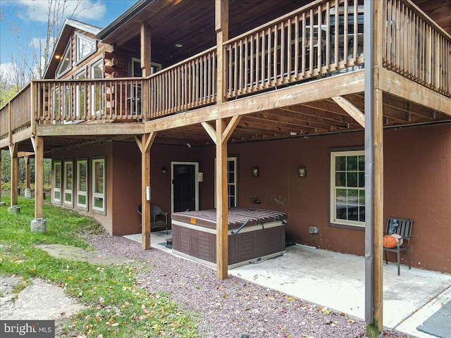 rear view of house with a patio area, a wooden deck, and a hot tub