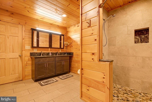 bathroom featuring tiled shower, vanity, wooden walls, and wood ceiling