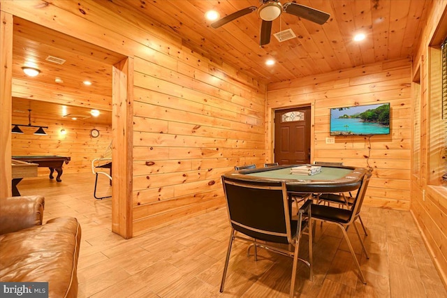 dining space featuring ceiling fan, wooden ceiling, wooden walls, and light hardwood / wood-style flooring