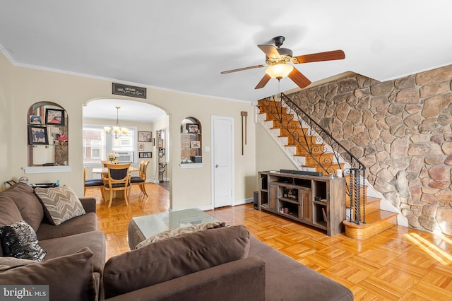 living room with ornamental molding, parquet flooring, and ceiling fan with notable chandelier