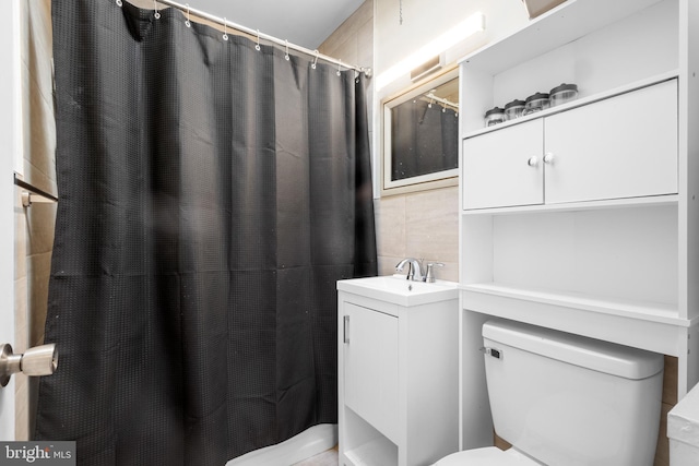 bathroom with a shower with curtain, vanity, toilet, and tile walls