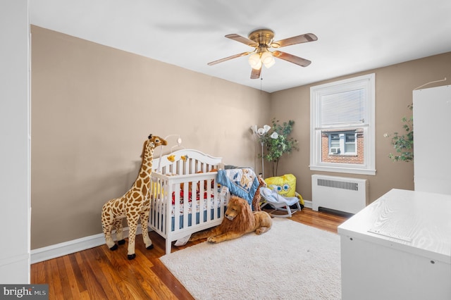 bedroom with dark wood-type flooring, radiator heating unit, and ceiling fan